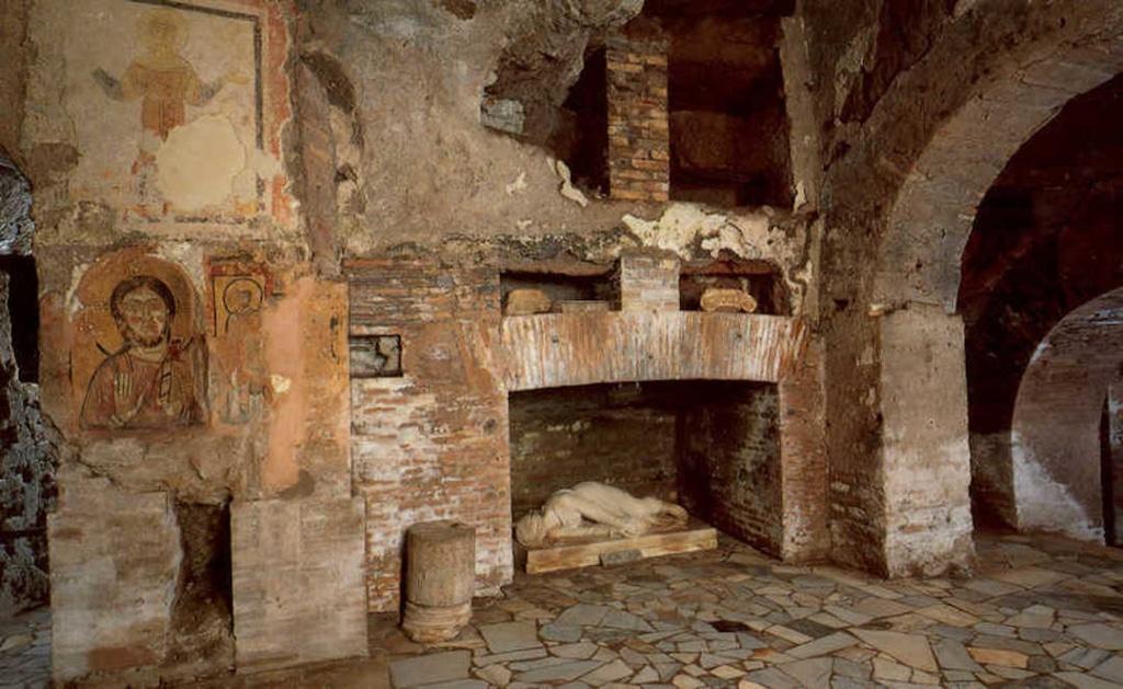 Intérieur des catacombes de Saint Calixte. On voit plusieurs niches creusées avec une statue allongée dans l'une d'elle.