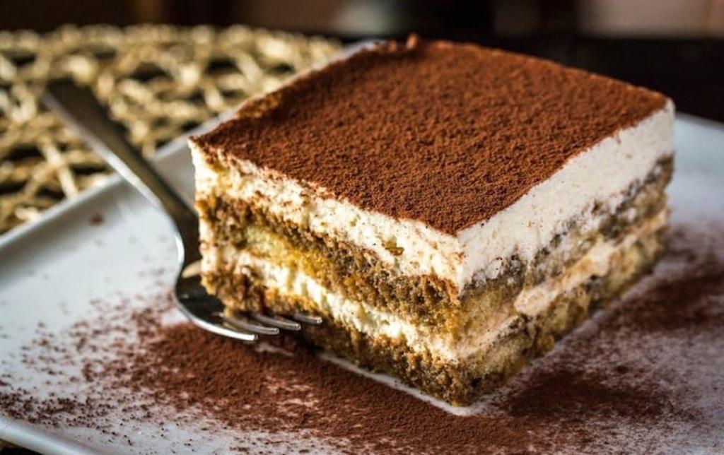 Part de tiramisu sur une assiette avec une fourchette à côté