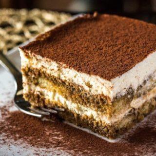 Part de tiramisu sur une assiette avec une fourchette à côté