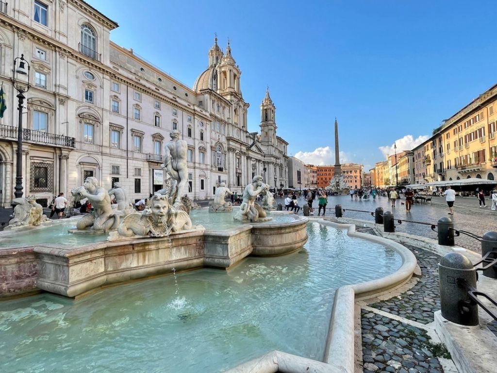 Fontaine de la Piazza Navona en premier plan avec église et obélisque en second plan